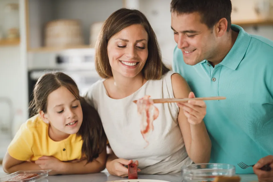 Une mère, un père et leur fille cuisinent ensemble en riant