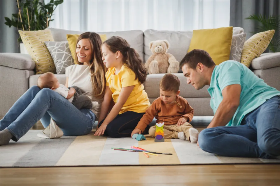 Une famille joue par terre dans le salon avec ses trois enfants